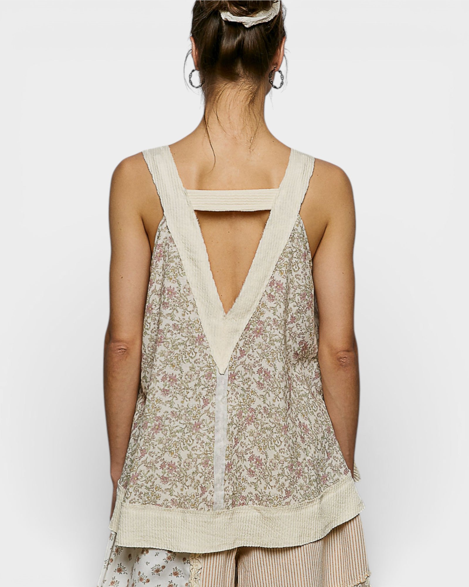 Woman wearing a floral sleeveless top with a V-neckline on a white background