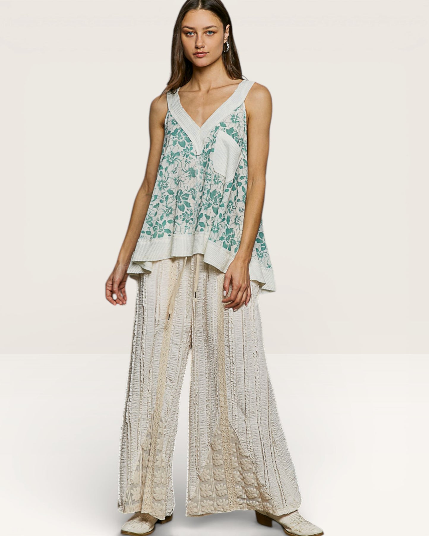 Woman wearing a floral top and wide-leg pants on a white background