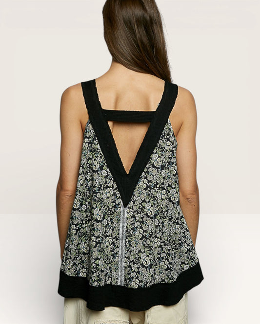 Woman wearing a floral tank top with black trim on a plain background