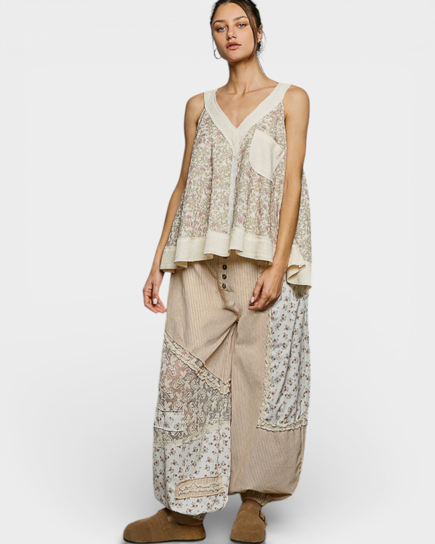 Woman wearing a layered outfit with a floral top and wide-leg pants on a white background