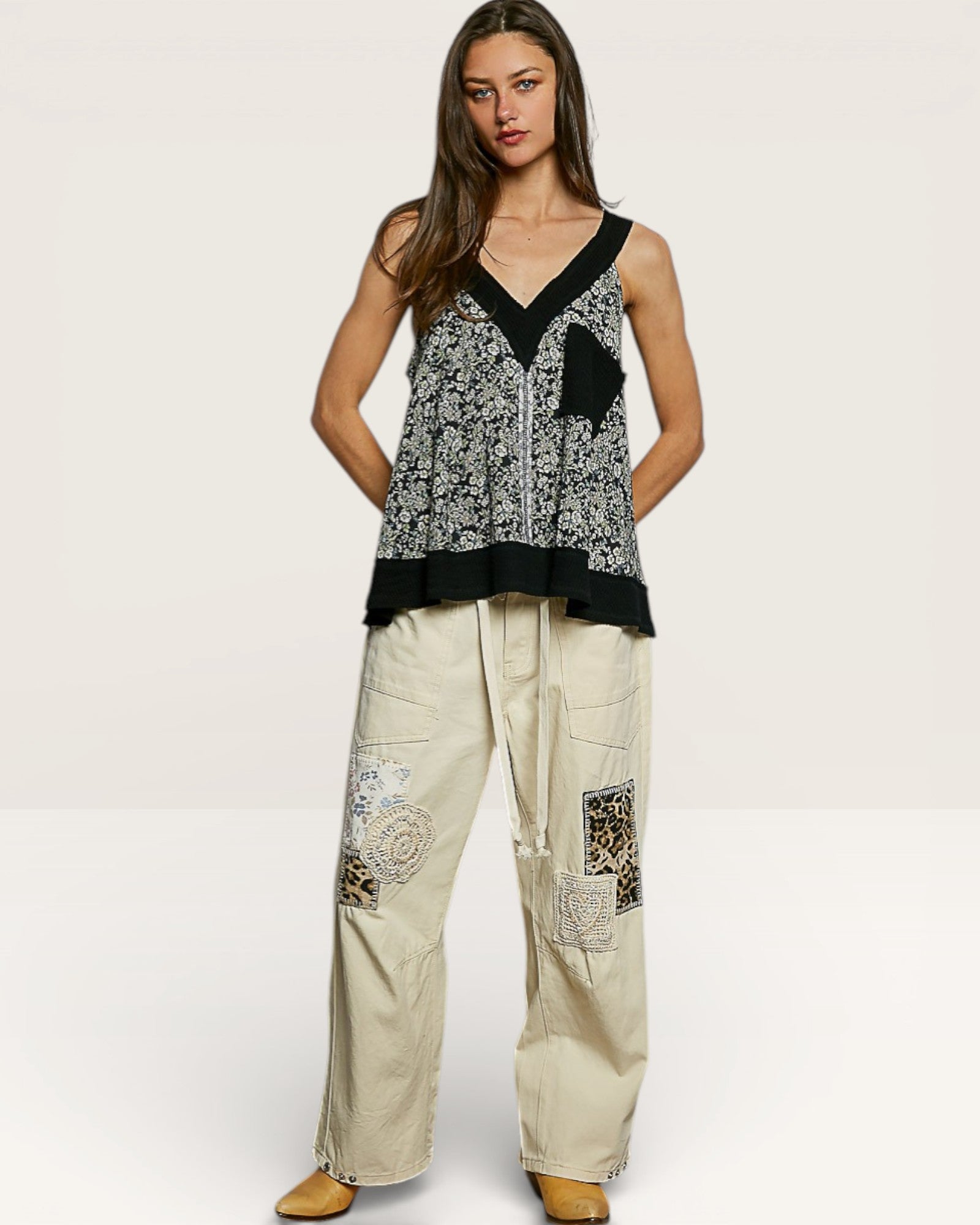 Woman wearing a black and white patterned top with beige pants on a white background