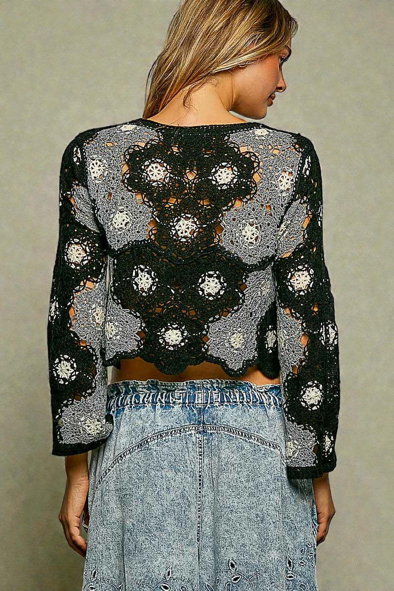 Woman wearing a black and gray crochet top with a plain background