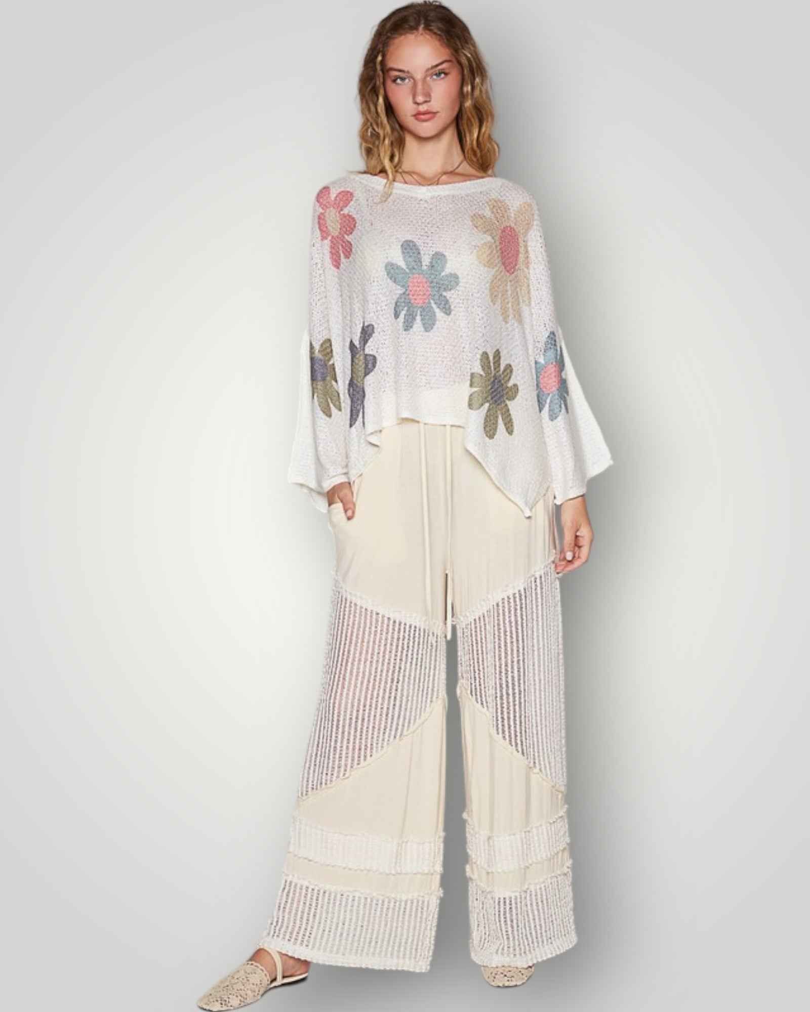 Woman wearing a floral blouse and wide-leg pants on a plain background