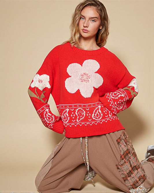 Woman wearing a red sweater with white floral patterns on a beige background