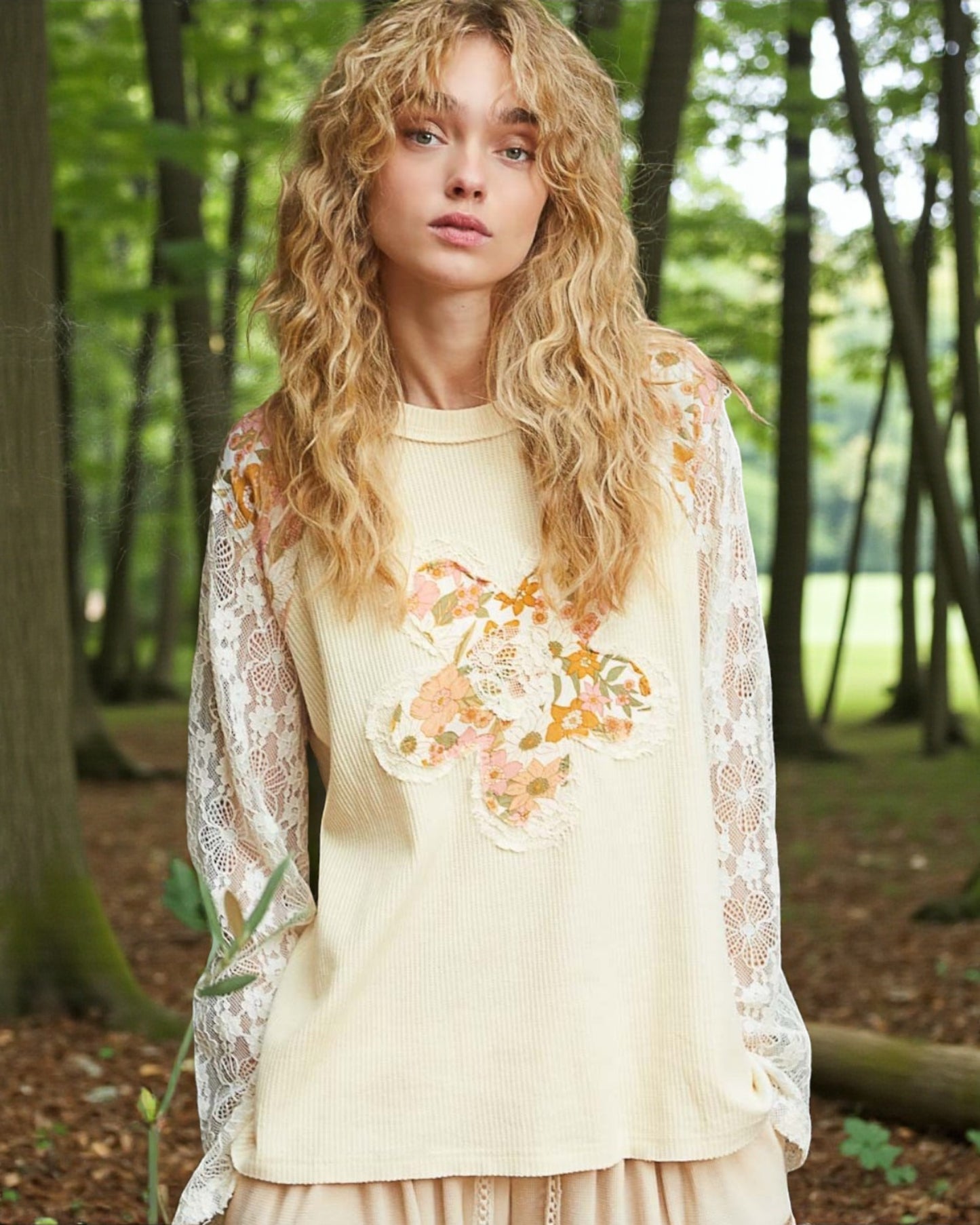 Woman wearing a floral top and lace cardigan in a forest setting