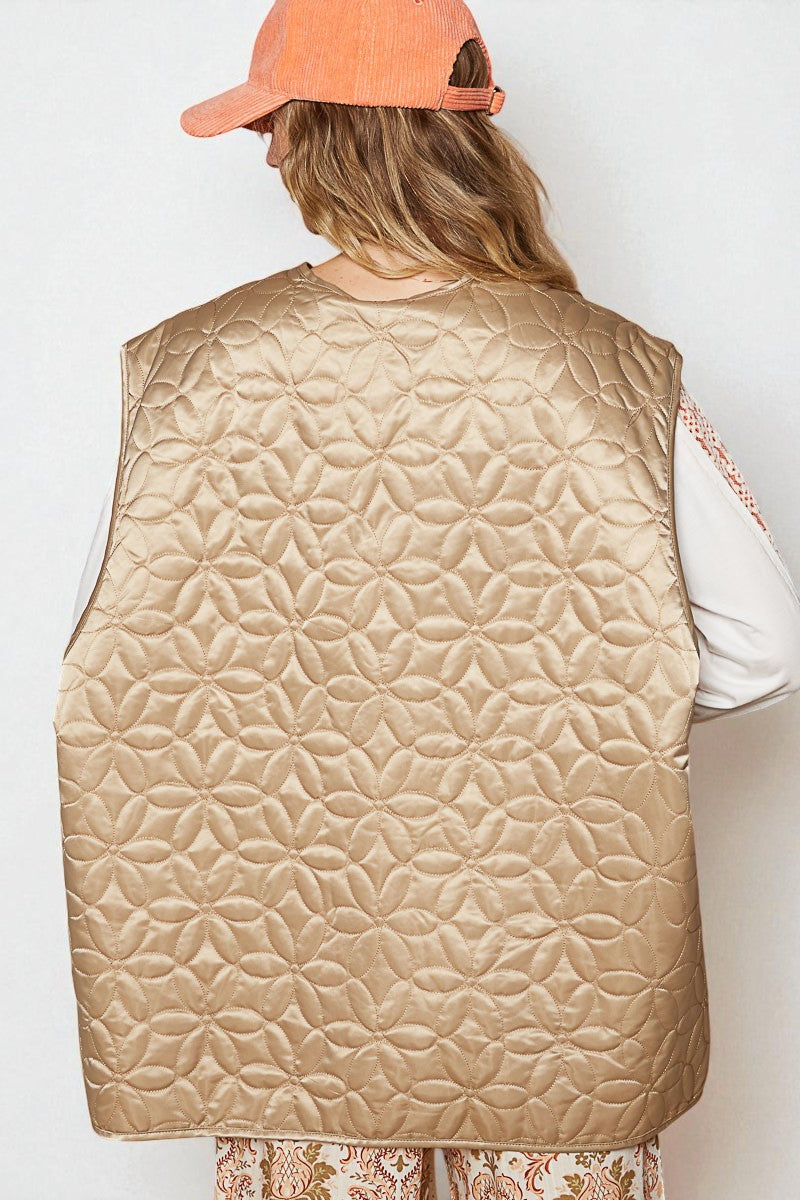Person wearing a beige quilted vest and an orange cap on a white background