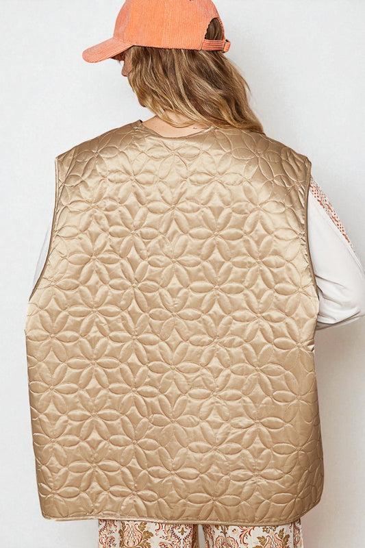 Person wearing a beige quilted vest and an orange cap on a white background