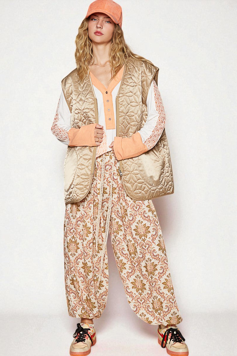 Person wearing a quilted vest, floral pants, and colorful shoes on a white background