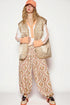Person wearing a quilted vest, floral pants, and colorful shoes on a white background