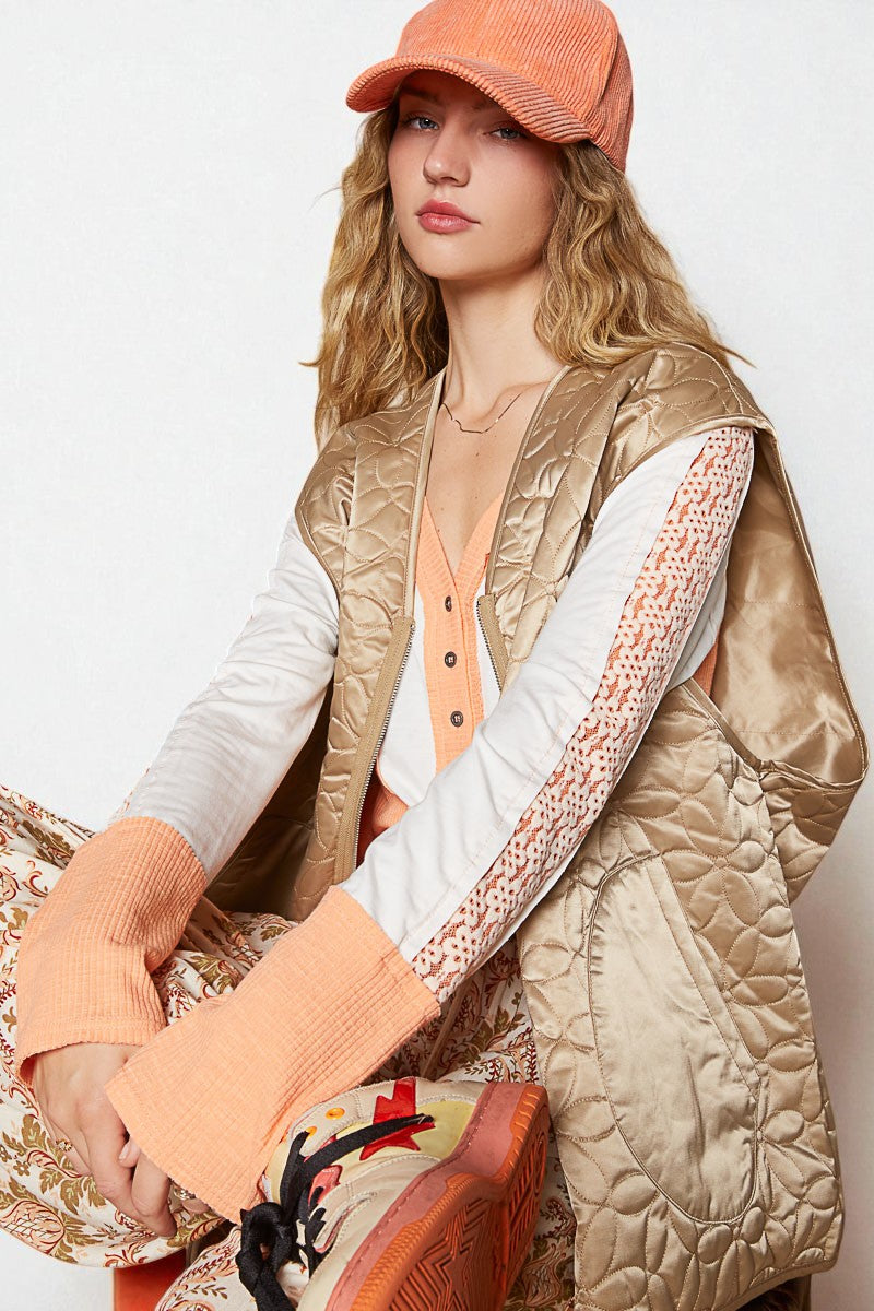 Woman wearing a gold quilted vest, orange cap, and patterned shoes on a light background