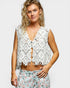 Woman wearing a white lace top with floral pants on a plain background