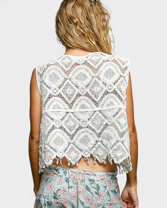 Person wearing a white lace top with a plain background