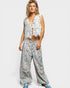 Woman wearing a white lace top and floral pants on a white background