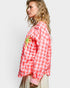Woman wearing a red and white checkered shirt with a palm tree design on a plain background