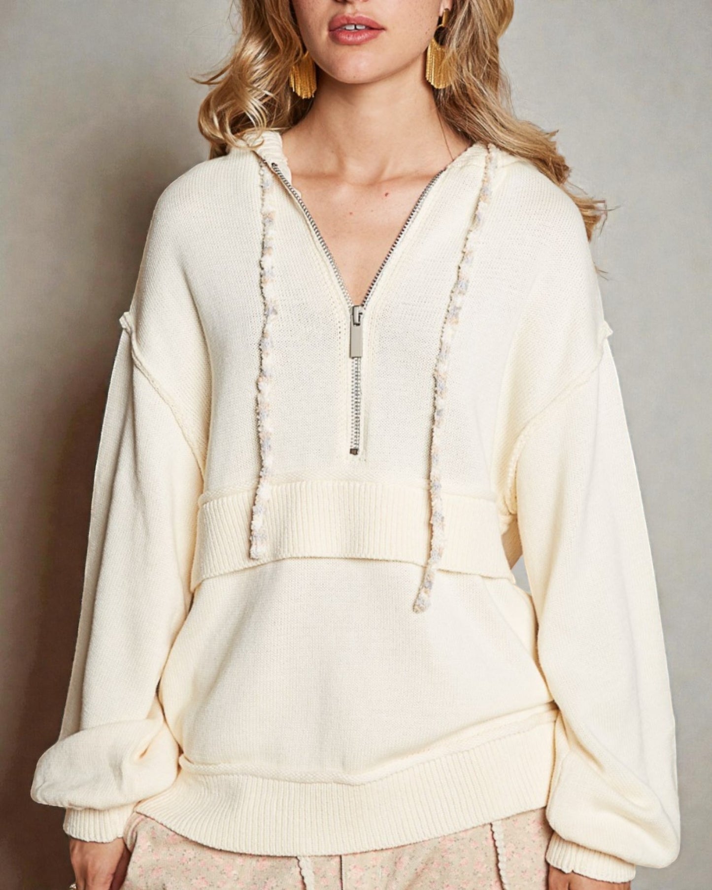Cream-colored zip-up hoodie worn by a person against a neutral background