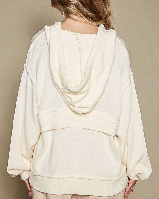 White hoodie worn by a person on a beige background