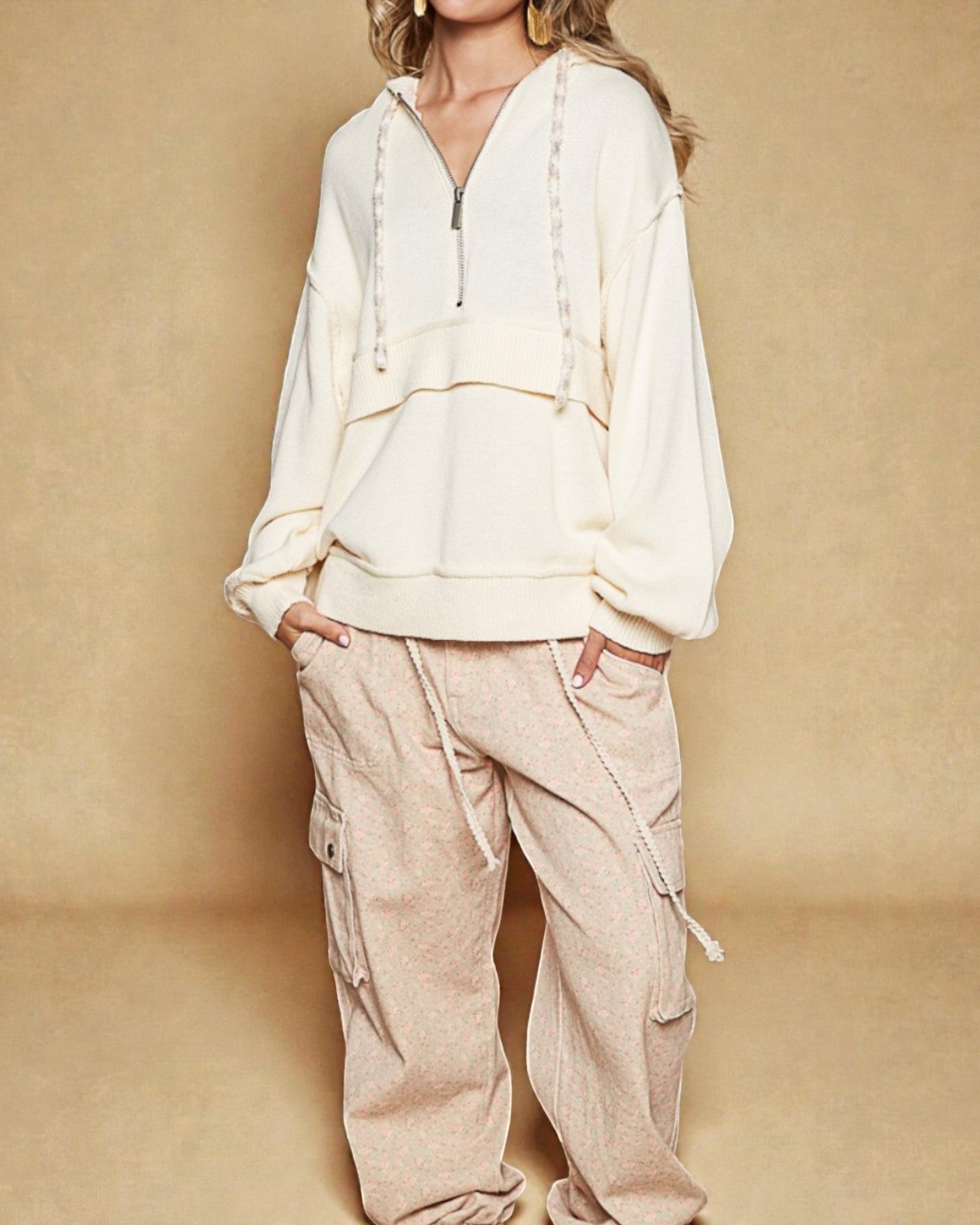 Person wearing a cream-colored hoodie and beige cargo pants against a beige background