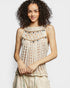 Woman wearing a beige crochet top against a plain background