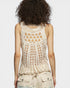Person wearing a beige crochet tank top on a plain background