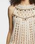 Close-up of a beige crochet dress with black button details on a white background
