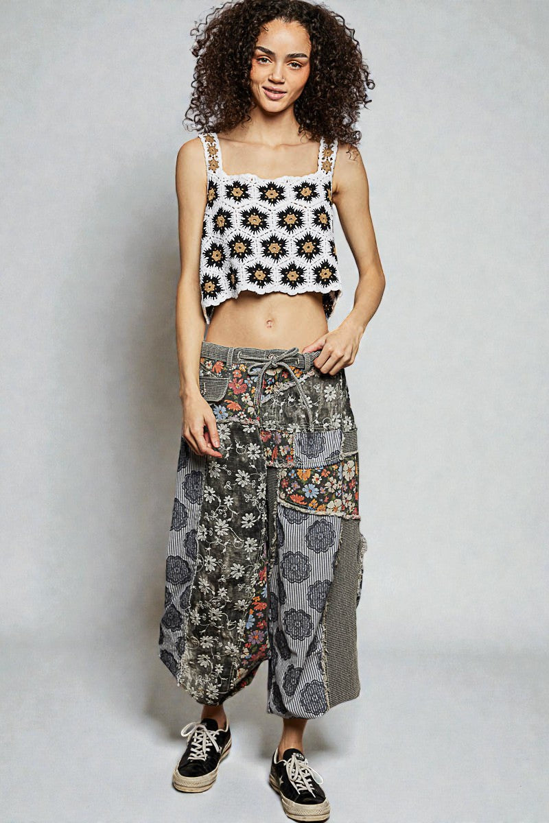 Woman wearing a floral tank top and patterned pants on a plain background