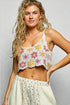 Woman wearing a colorful crochet top with a plain background