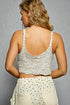Woman wearing a light-colored crochet top and skirt against a gray background