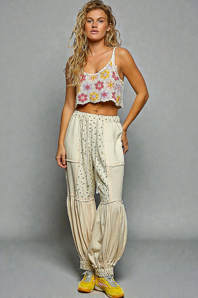 Woman wearing a floral crop top and wide-leg pants on a gray background