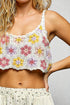 Woman wearing a colorful crochet top with a plain background
