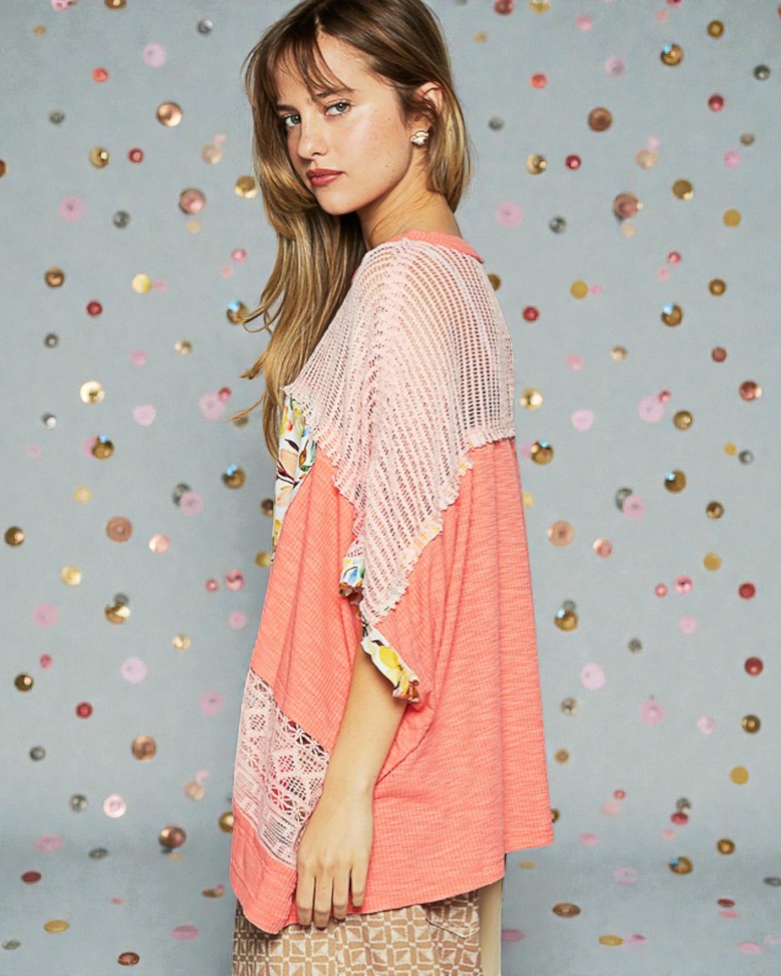 Woman wearing a pink and coral outfit with a patterned background