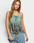 Woman wearing a green lace-up top with fringe details and blue jeans on a white background