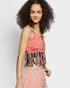 Woman wearing a pink top with fringe details on a plain background
