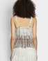Person wearing a white dress with colorful fringe details on a plain background