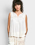 Woman wearing a white sleeveless top with lace details against a plain background
