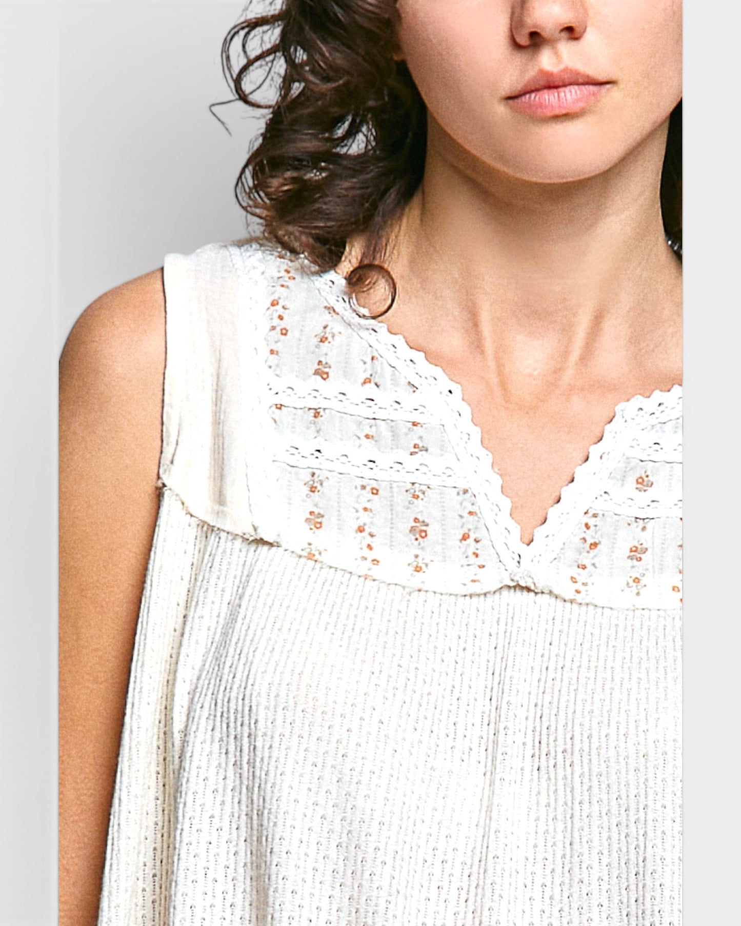 Close-up of a woman wearing a white lace top against a gray background