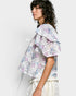 Woman wearing a floral blouse with ruffled sleeves on a white background