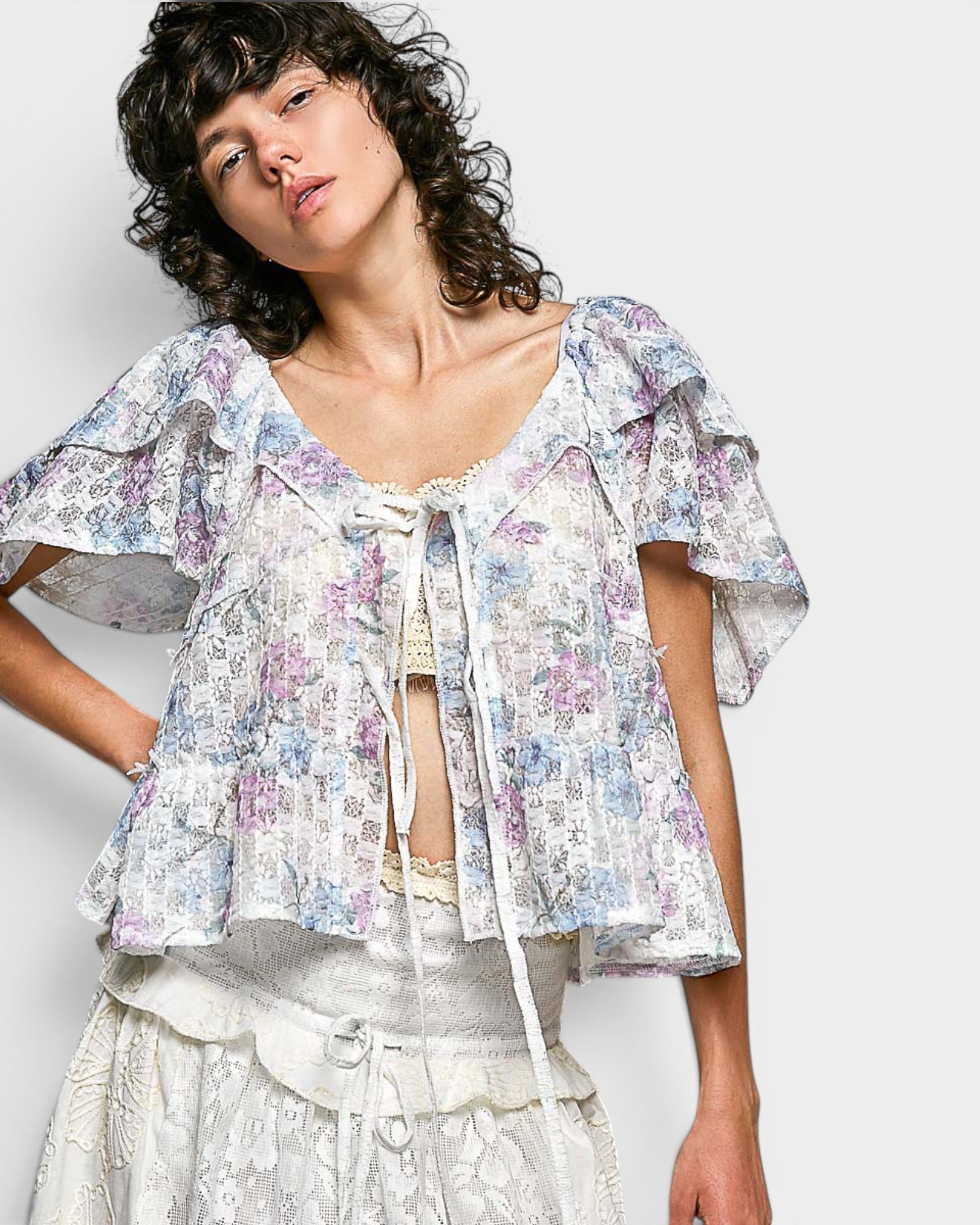Woman wearing a floral blouse with ruffled sleeves against a plain background
