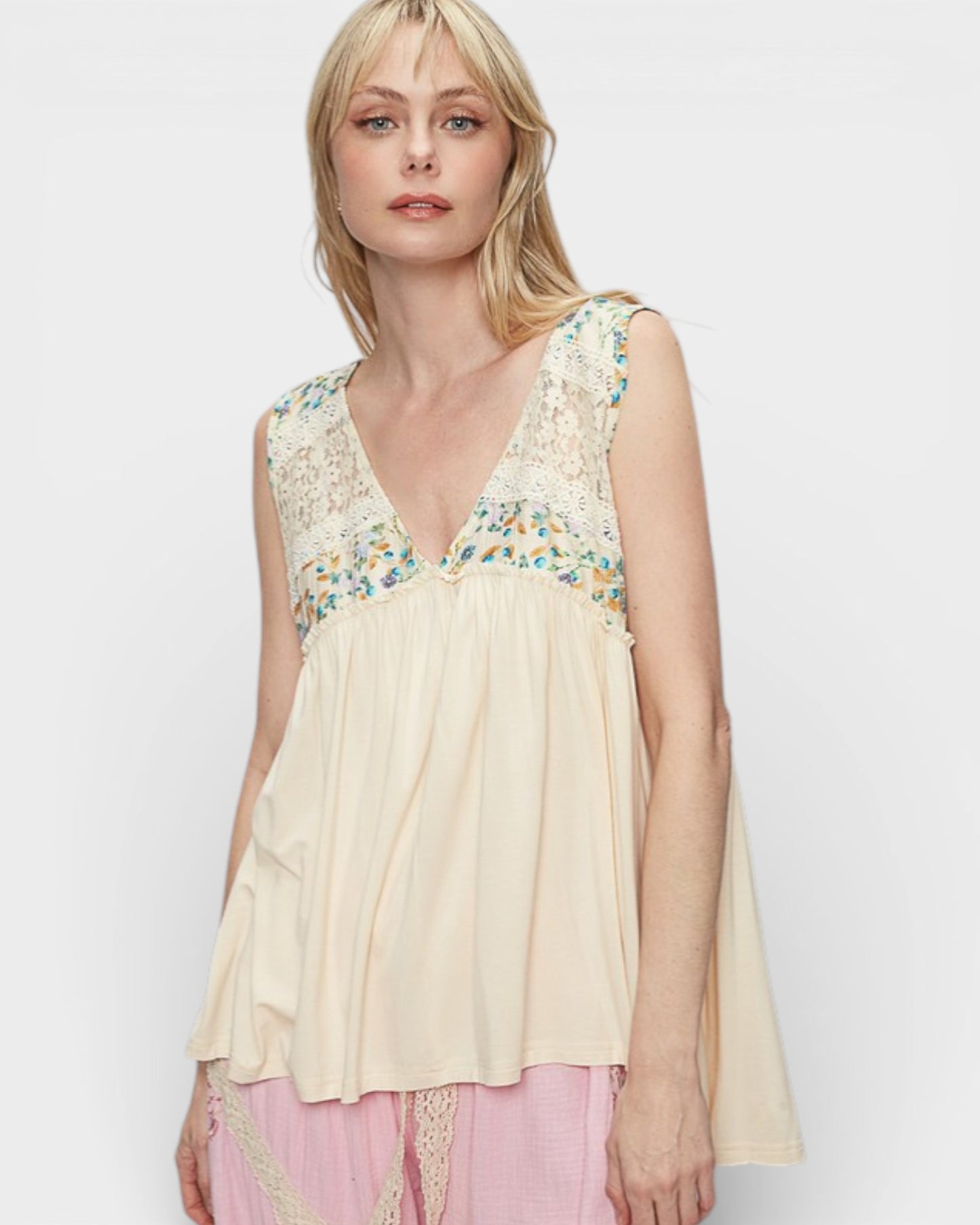 Woman wearing a beige sleeveless top with floral embroidery on a white background