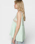 Woman wearing a light green sleeveless top with floral embroidery on a white background