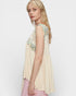 Woman wearing a beige sleeveless top with floral embroidery on a white background