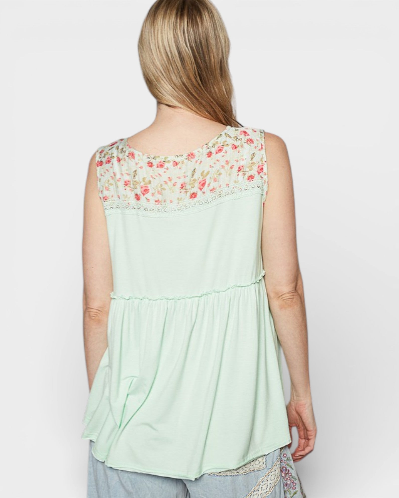 Light green sleeveless top with floral lace details on a plain background