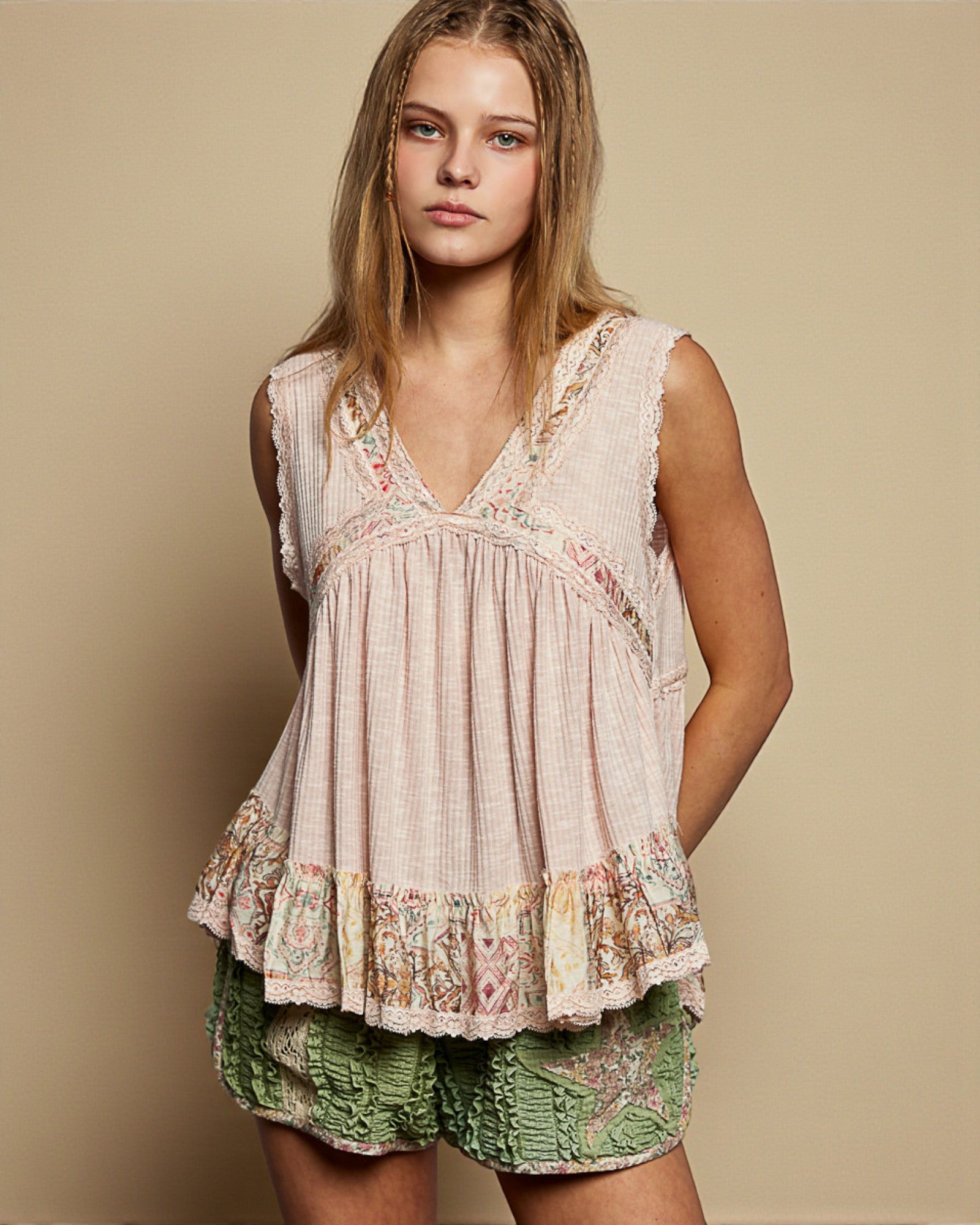 Woman wearing a sleeveless top and green shorts against a beige background