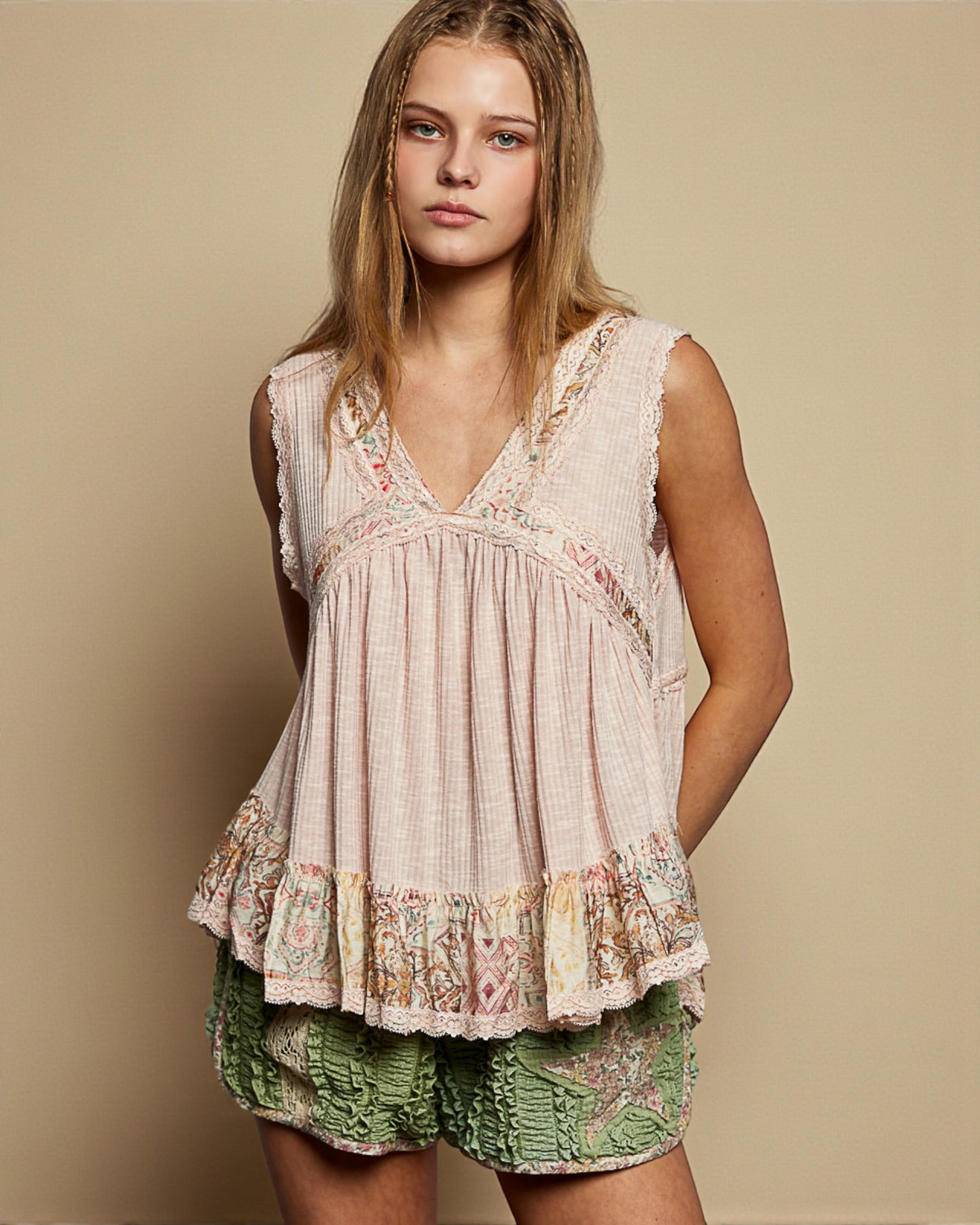 Woman wearing a sleeveless top and green shorts against a beige background