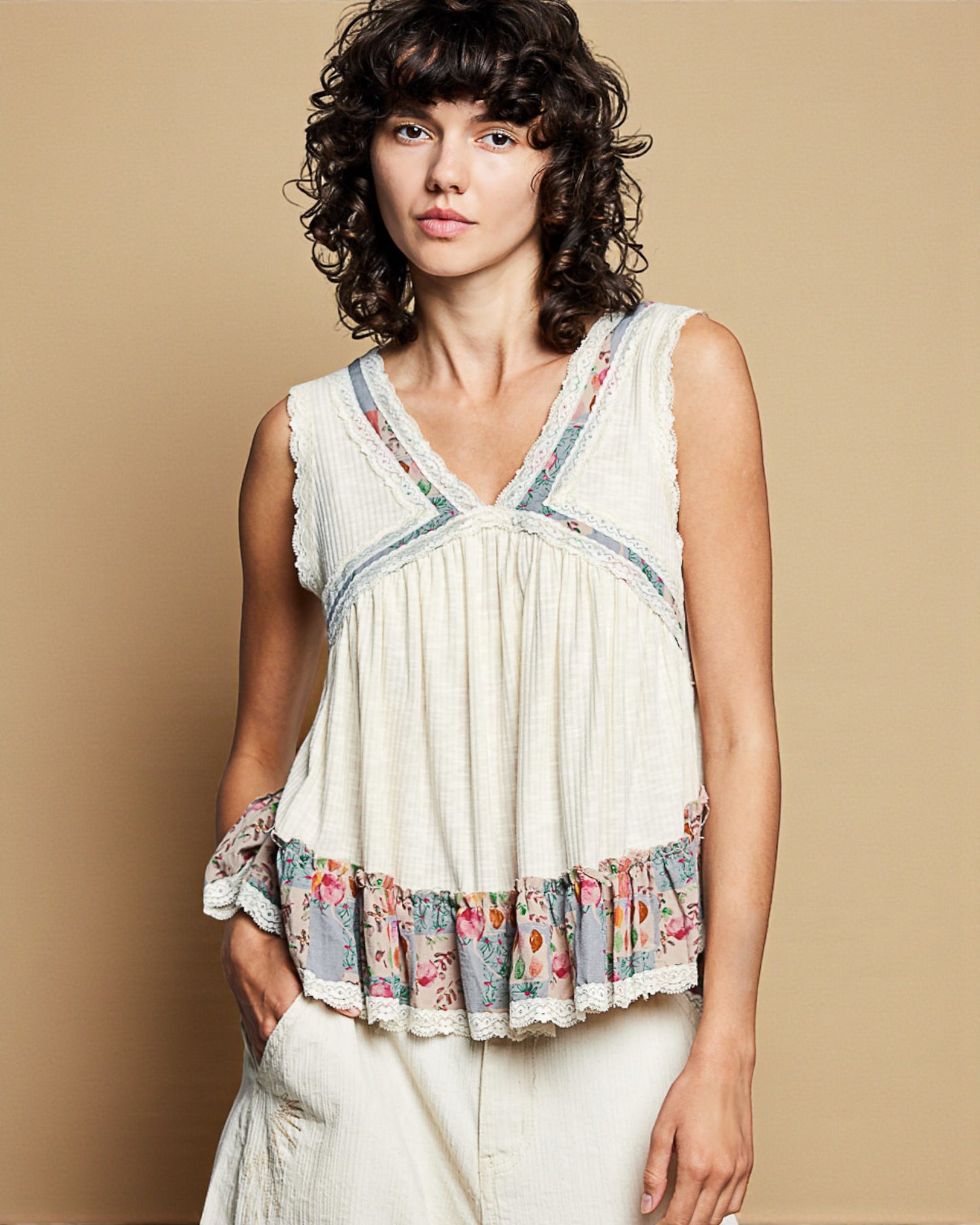 Woman wearing a sleeveless top with floral patterns against a beige background