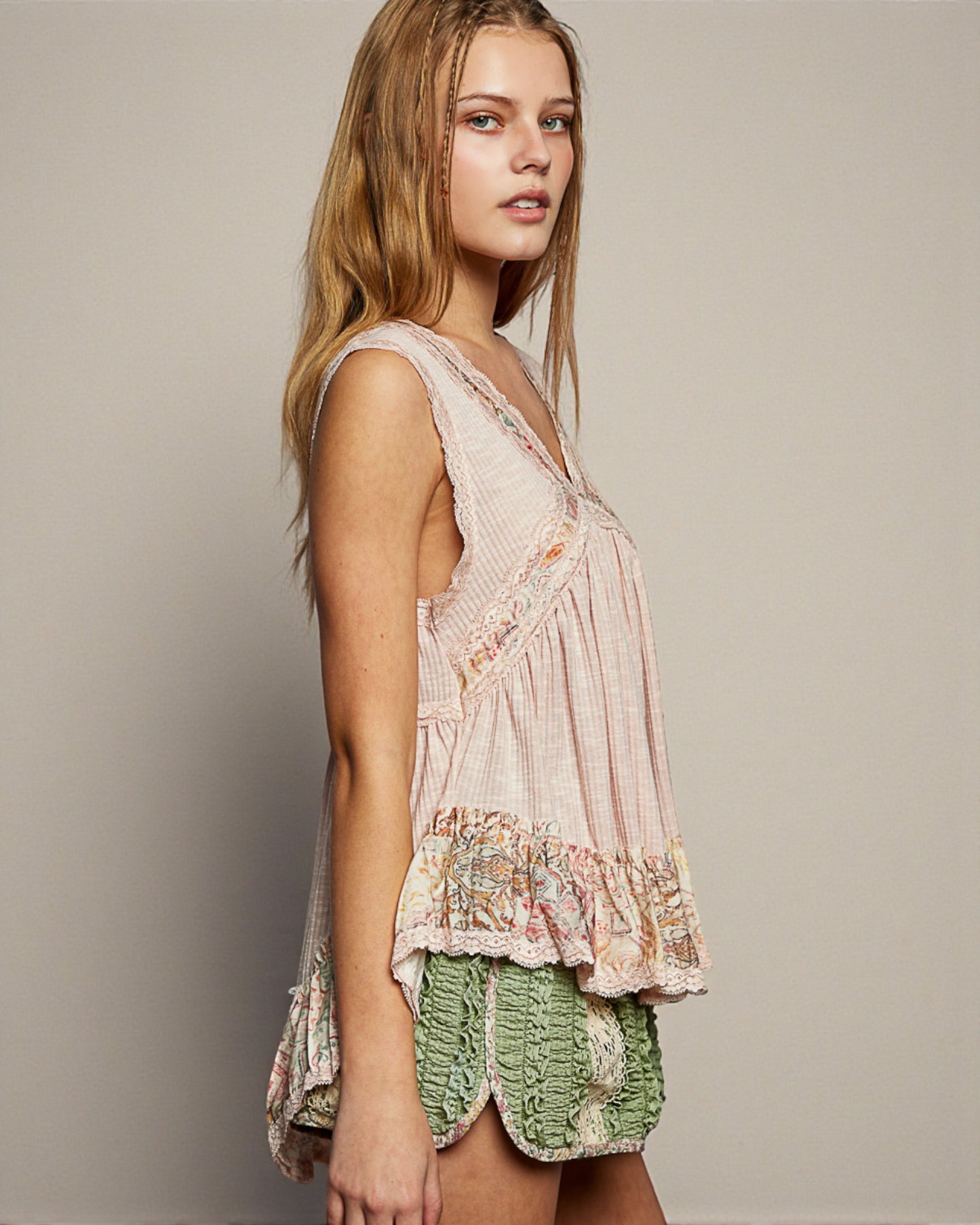 Woman wearing a floral top and green shorts against a plain background