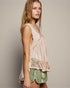Woman wearing a floral top and green shorts against a plain background