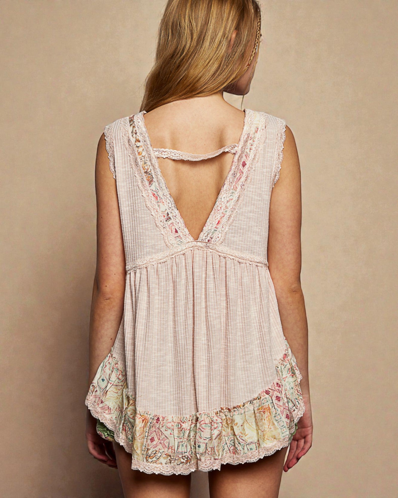 Woman wearing a sleeveless, floral-patterned dress with a beige background