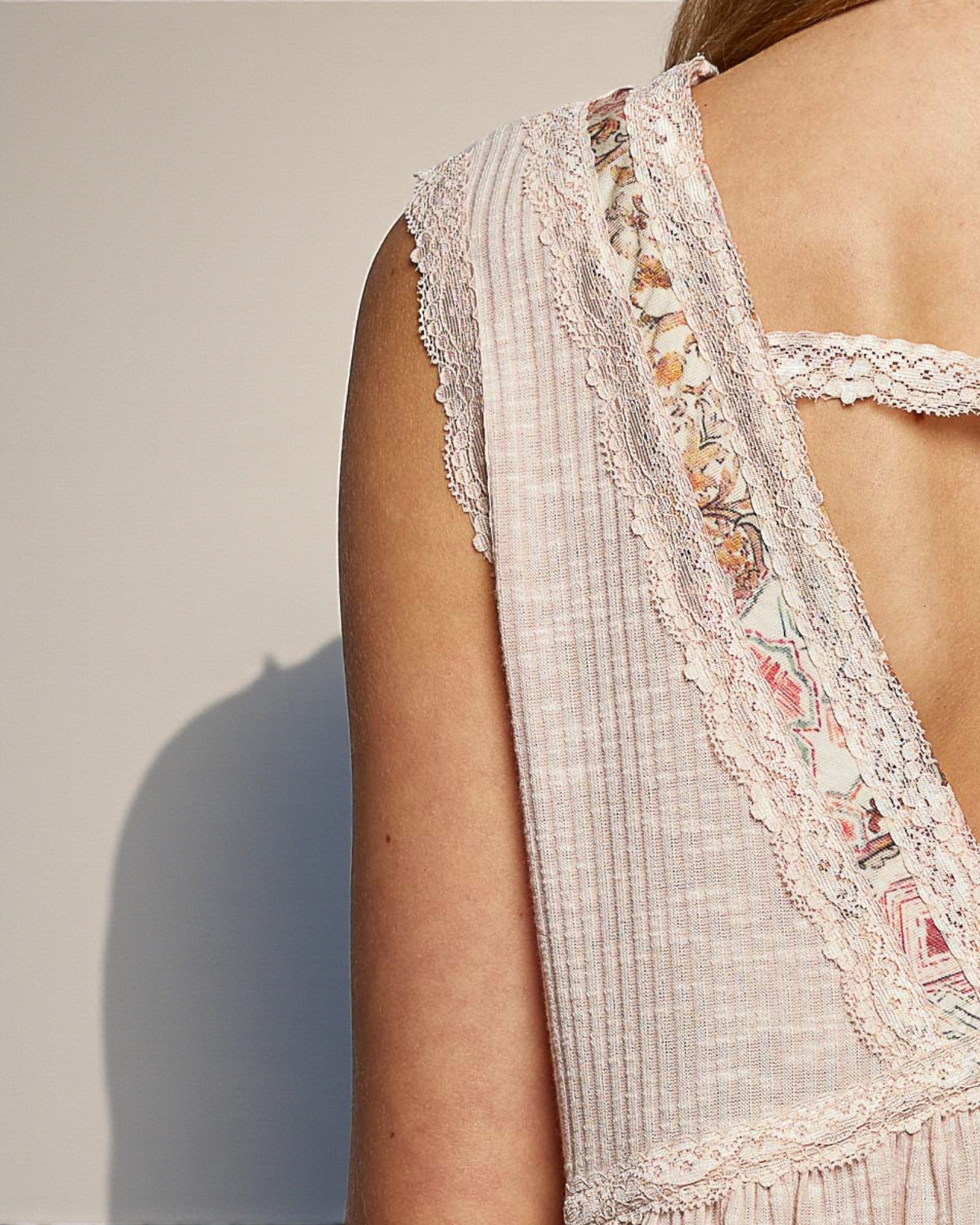 Close-up of a person wearing a light-colored dress with lace details on a neutral background
