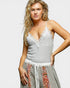 Woman wearing a gray lace-trimmed top with a colorful skirt on a white background