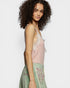 Woman wearing a pink lace top and green embroidered skirt on a white background